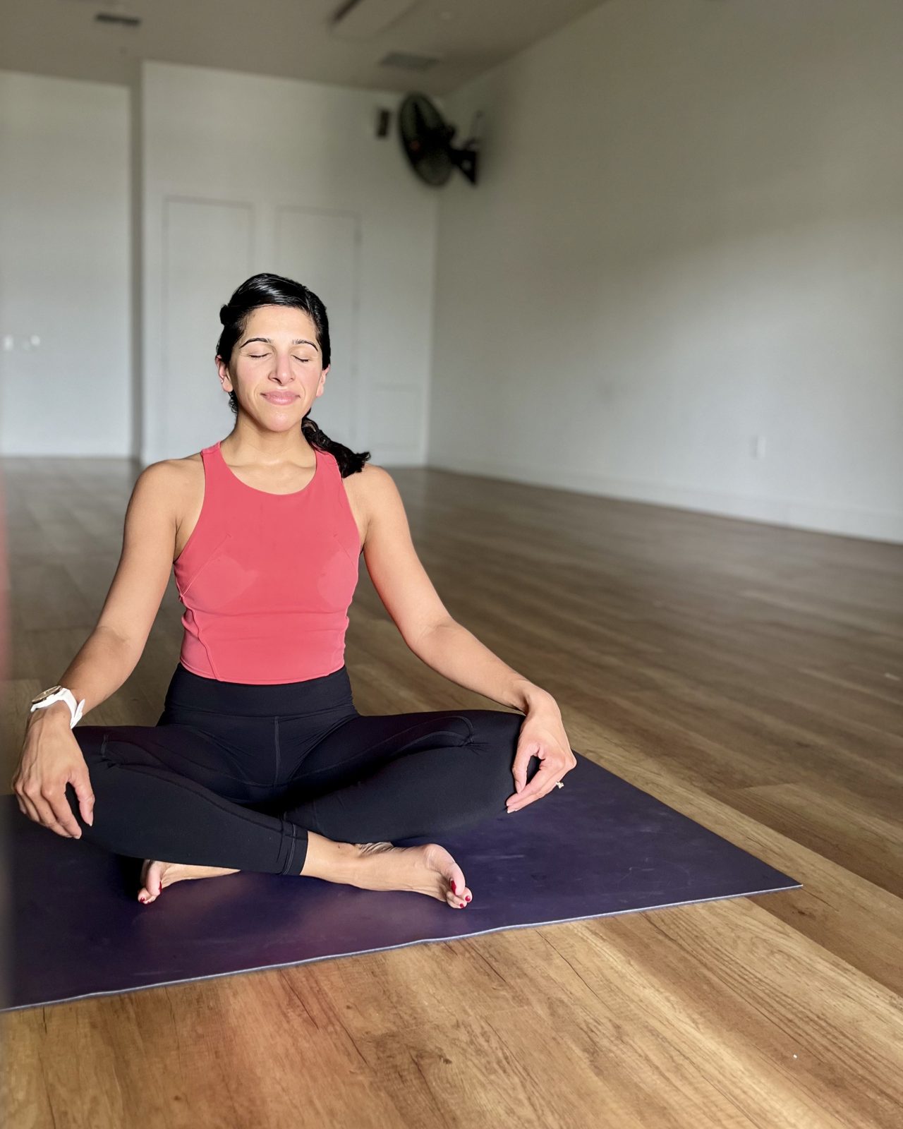 Dr. Priya Mathews meditating on a yoga mat